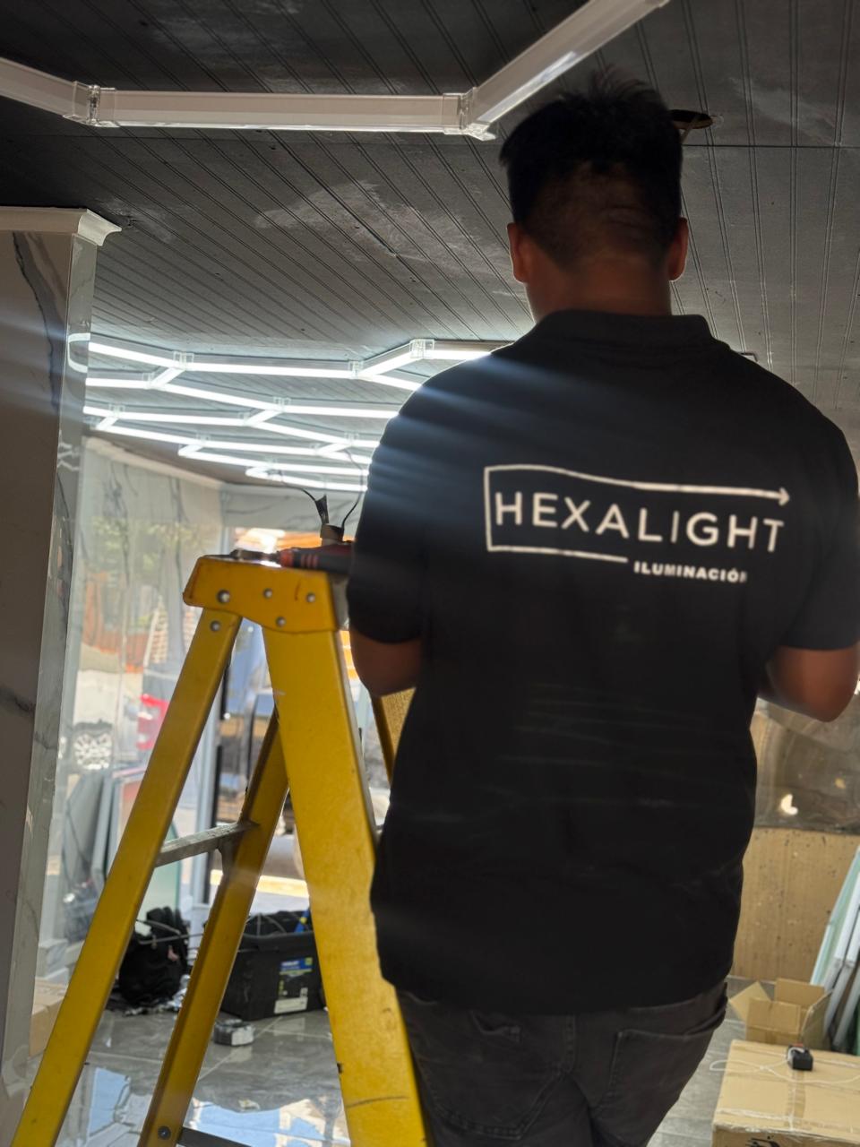 Técnico HexaLight en escalera marcando puntos de fijación para paneles LED en techo